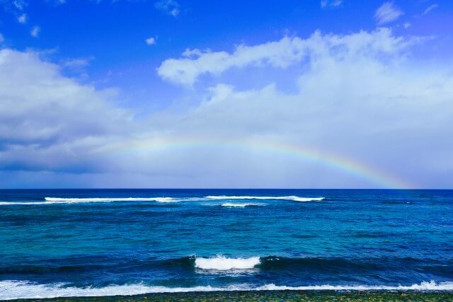 ハワイ穏やかなノースショアの海と水平線にかかる虹